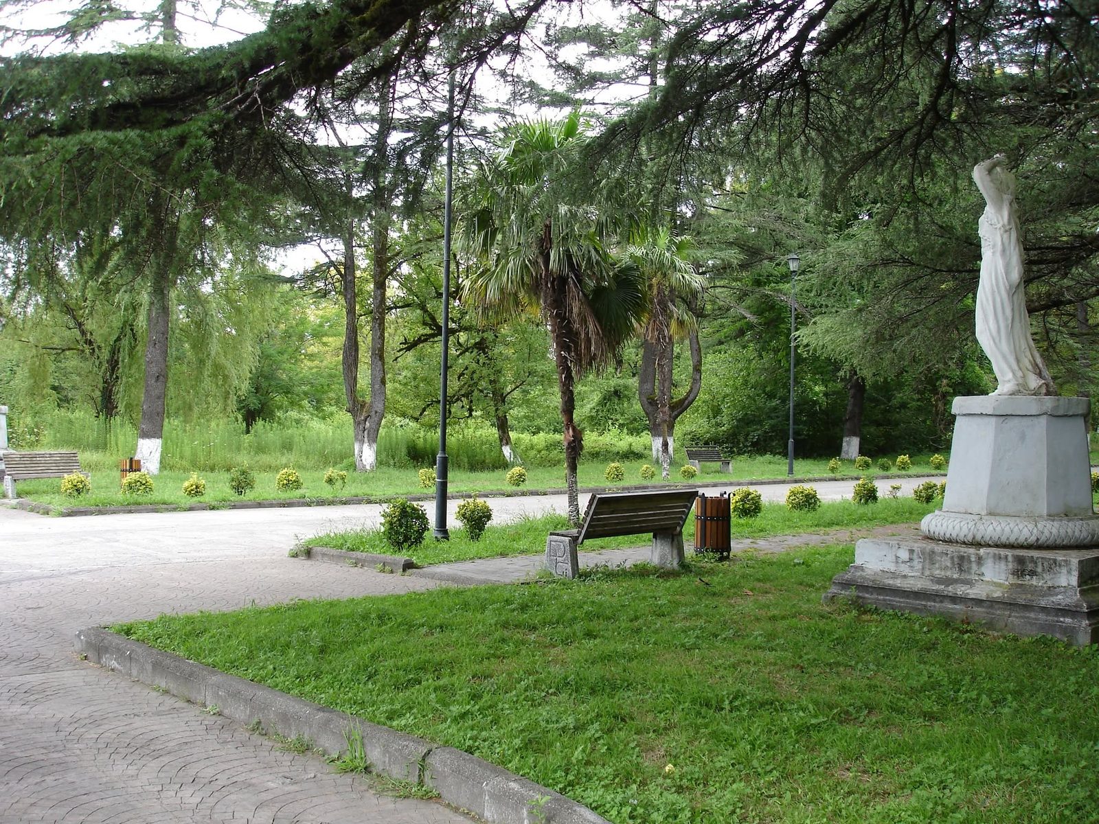 The town park: flower beds, benches and a marble statue by the path.