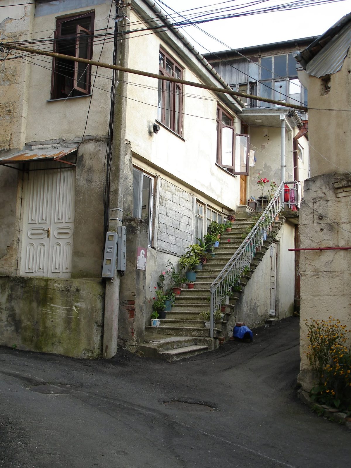 An old courtyard with an outside staircase and flowers on the steps.