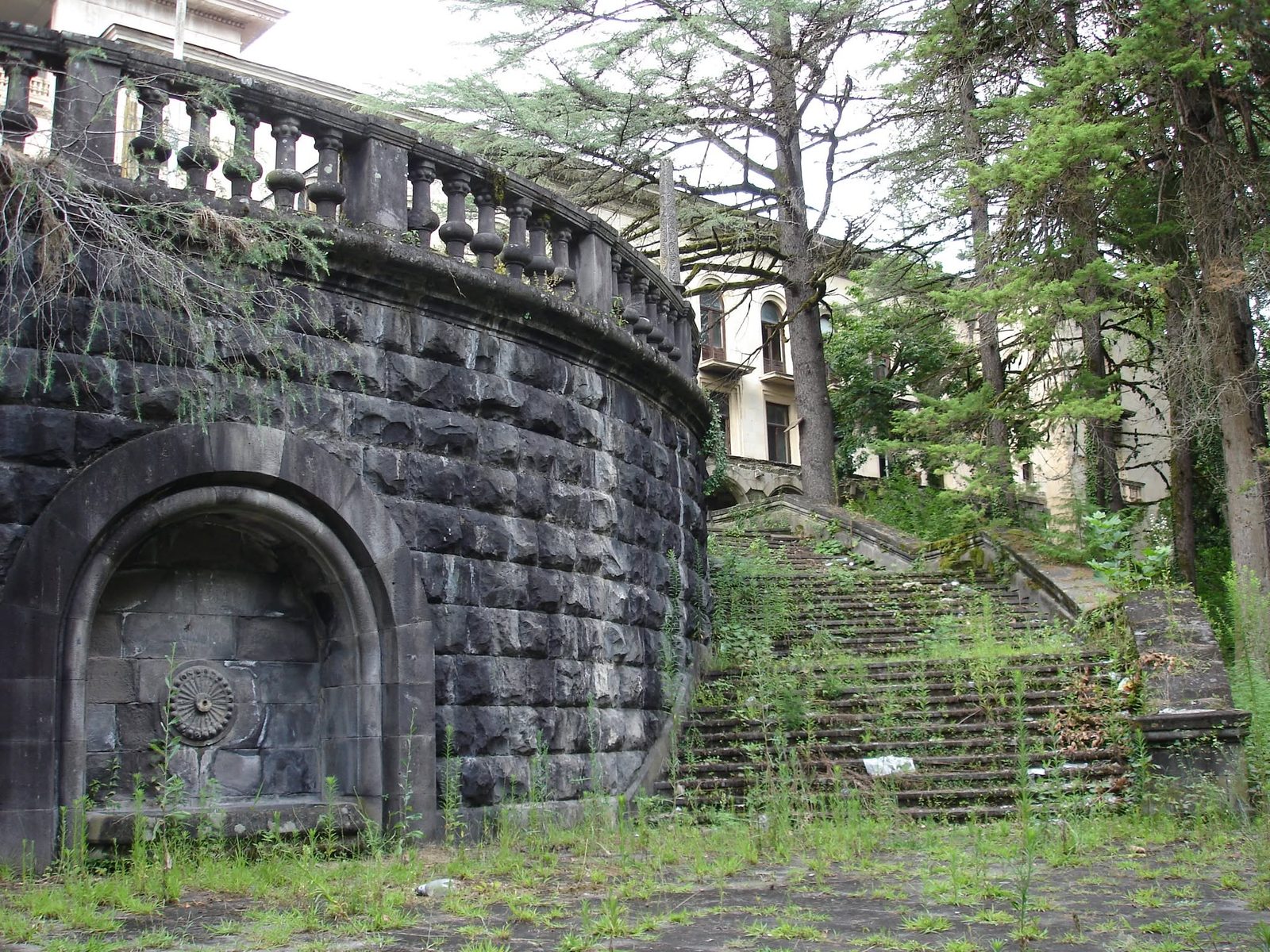 A stone wall with an arched niche and steps leading up.