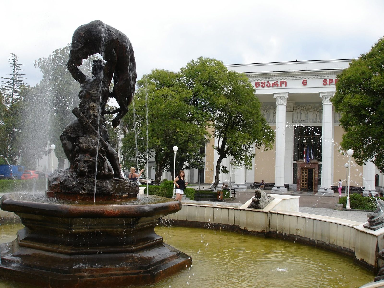 A fountain with a sculpture in front of a building with columns.